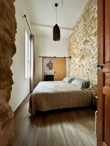 sypialnia z łóżkiem i kamienną ścianą w obiekcie Pasaje San Fernando w Alicante