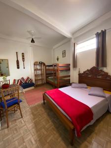 a bedroom with a large bed with a red blanket at Casa Tribus Itamambuca in Ubatuba