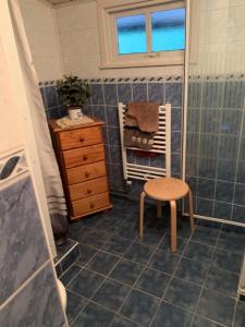 a bathroom with a shower and a chair and a sink at Witte wieven bungalow 17 in Nunspeet