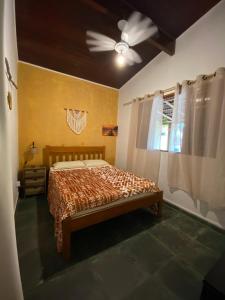 a bedroom with a bed and a ceiling fan at Casa Tribus Itamambuca in Ubatuba