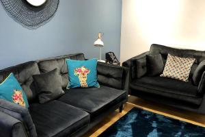 a living room with a black couch and blue pillows at Sitwell coastal apartment with free parking in Scarborough