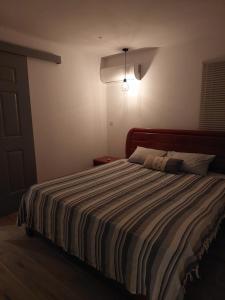 a bedroom with a large bed with a striped comforter at AJ Studio Apartment in Moka