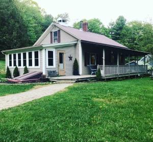 a white house with a porch on a green lawn at Hiking, MTB, four wheeling, fishing lakes, beaches, skiing, snowboarding, in Barton