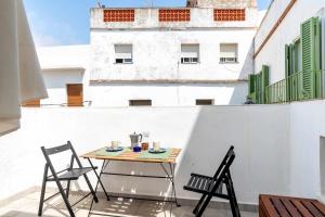 a table and chairs on a balcony with a building at Erizo 3 loft diafáno en el Centro Histórico in Tarifa