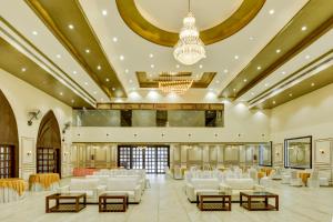 um grande salão de banquetes com cadeiras brancas e um lustre em Treebo Trend Winsome Banquet And Resort em Ranchi