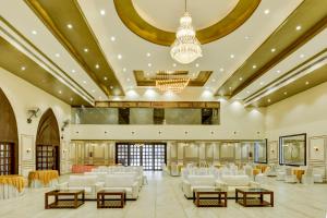 a large banquet hall with white chairs and a chandelier at Treebo Winsome Banquet And Resort in Rānchī