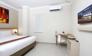 a white room with a bed and a desk and a table at Laxston Hotel in Yogyakarta