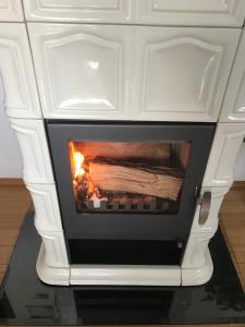 a white stove with a fire inside of it at Apartman Bosco in Ravna Gora