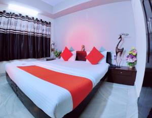 a bedroom with a large bed with red and white sheets at HOTEL HARMONY in Jamnagar