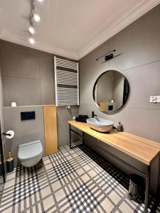 W łazience znajduje się umywalka, toaleta i lustro. w obiekcie LuxApart Kalisz V.I.P w Kaliszu