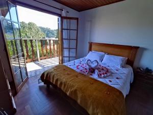 1 dormitorio con cama y ventana grande en Pousada Campos de Paiva, en Campos do Jordão