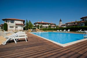 una piscina con sedie a sdraio accanto a un edificio di Bell Tower at BlackSeaRama Golf&Villas a Balchik