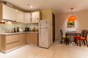 a kitchen with a refrigerator and a table with chairs at The Rixx Indochine Apartment with Balcony and Rooftop Pool in Ho Chi Minh City