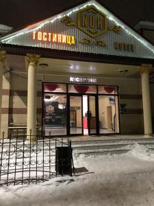 a building with a sign on it in the snow at Гостиница NUR in Aralʼsk