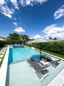 a swimming pool with two chairs and an umbrella at House Of Art - Luxury Villa with Pool & Jacuzzi! in Tamiami