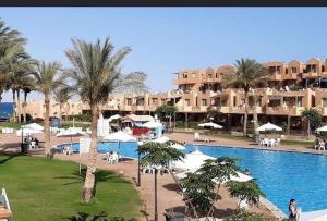 ein Resort mit einem Pool, Palmen und Gebäuden in der Unterkunft Chalet first floor two bedrooms In Stella De Mare Ain El Sokhna For Families only in Ain Suchna