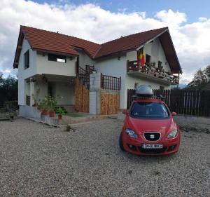 un pequeño coche rojo estacionado frente a una casa en La Păstravaria Cerna, en Rîu de Mori