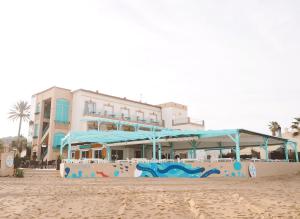 a building with blue umbrellas on the beach at Hotel Noguera Mar in Denia