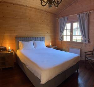 - une chambre avec un grand lit blanc et 2 fenêtres dans l'établissement Riverside Forest Retreat-Chalet, à Karpenísi