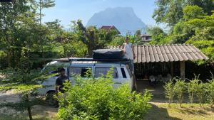 a man standing on the roof of a van at Brown House Chiangdao in Chiang Dao