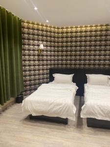 2 camas en una habitación con cortinas verdes en فندق المنصور, en Aḑ Ḑabbīyāt al Janūbīyāt