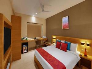 a bedroom with a large bed and a desk and a television at Hotel Suba Elite Vadodara in Vadodara