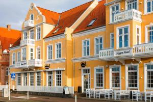 a yellow building with white windows and white tables at Skagen Villa & Apartments in Skagen