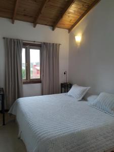 een slaapkamer met een wit bed en een raam bij Casa Bordó, B & B in Tandil