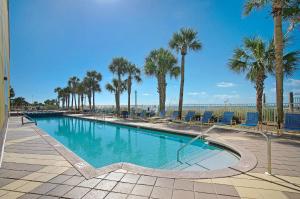 巴拿马城海滩Beachfront - Private Balcony - Near Pier - FLPCB62的一个带棕榈树和椅子的游泳池以及海滩