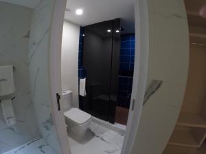 a white bathroom with a toilet and a shower at WeEnjoy Hotels Grand Prix Aeropuerto CDMX in Mexico City