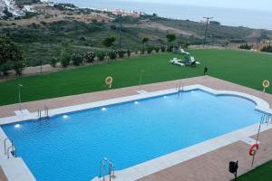 une grande piscine bleue à côté d'un champ verdoyant dans l'établissement Beautiful new apartment with direct sea view, FIRST LINE!!, à Manilva