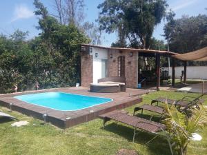 a swimming pool in a backyard with a deck and a house at Marina Guest House in Búzios