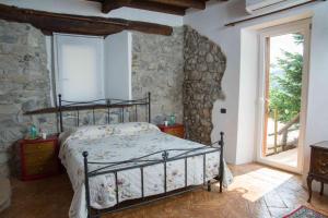 1 dormitorio con cama y pared de piedra en B&B la Curt del Böff, en Lasnigo