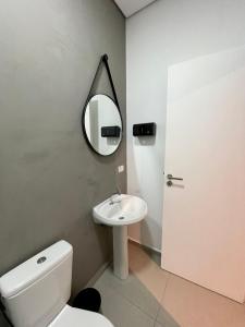 a bathroom with a white toilet and a mirror at Acomodações Tio Will in Guarujá