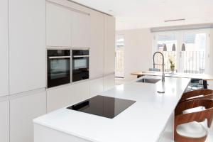 una cocina blanca con una gran encimera blanca en Fabulous Central Windsor Town House With Parking, en Windsor