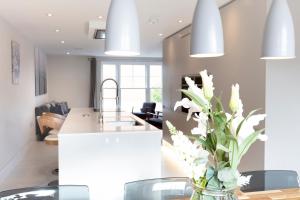 a kitchen with a table with white flowers in a vase at Fabulous Central Windsor Town House With Parking in Windsor