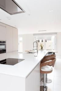 a white kitchen with a white counter and a sink at Fabulous Central Windsor Town House With Parking in Windsor
