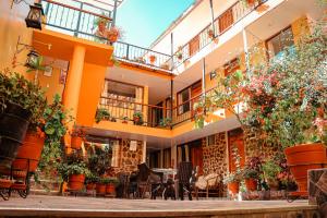 un edificio de apartamentos con plantas, mesas y sillas en Intitambo Hotel en Ollantaytambo