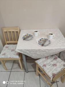 a table with two cups of coffee and two chairs at Evaggelia's Apartments 1 Διαμονή στο κέντρο in Kozani