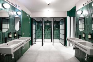 a bathroom with two sinks and green walls and mirrors at COEO Pod Hostel - Part of COEO Experience in Málaga