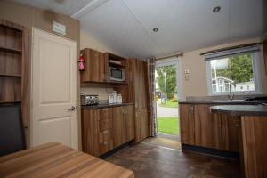 a kitchen with wooden cabinets and a door with a window at Willow View - Hoburne Cotswolds Holiday Park in South Cerney