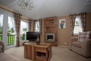 a living room with a tv and a couch and a table at Willow View - Hoburne Cotswolds Holiday Park in South Cerney