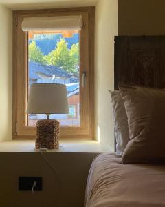 una cama con una lámpara junto a una ventana en Il Casias en Balme