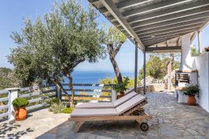 eine Terrasse mit einer Bank und dem Meer im Hintergrund in der Unterkunft Villa Rose in Glossa