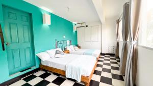 2 camas en una habitación con paredes azules y suelo a cuadros en Puerta Aqua by La Puerta Hostels, en Santa Marta