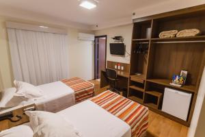 a hotel room with two beds and a television at JR Hotel Ribeirão Preto in Ribeirão Preto