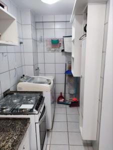 a small kitchen with a stove and a sink at Apartamento com piscina a uma quadra da praia de jatiuca in Maceió