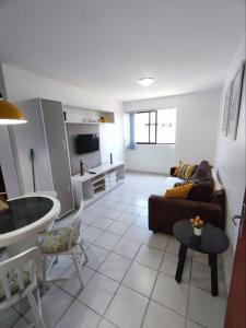 a living room with a couch and a kitchen at Apartamento com piscina a uma quadra da praia de jatiuca in Maceió