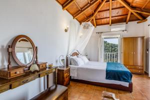 ein Schlafzimmer mit einem Bett, einem Spiegel und einem Fenster in der Unterkunft Villa Rose in Glossa