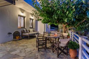 a patio with a table and chairs and a tree at Villa Rose in Glossa
